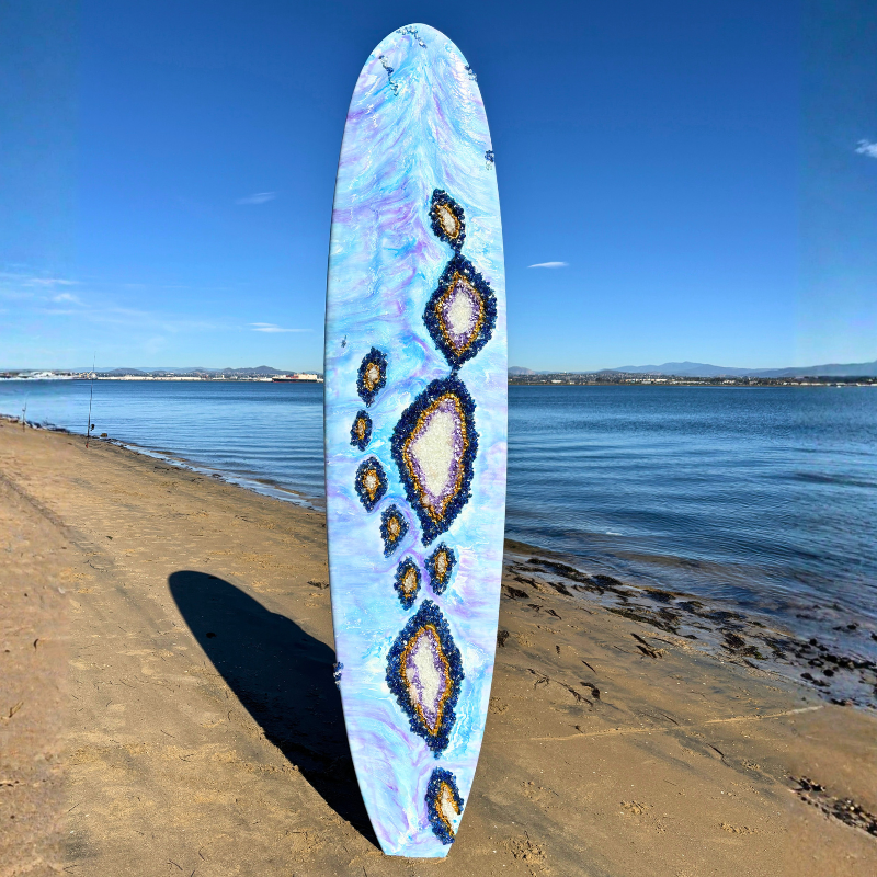 9 ft longboard with blue and purple epoxy resin hues adorned with crystal quartz glass and geodes